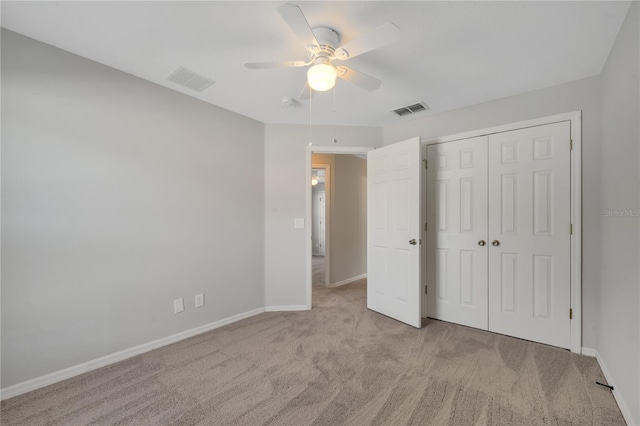 unfurnished bedroom featuring a closet, light colored carpet, and ceiling fan