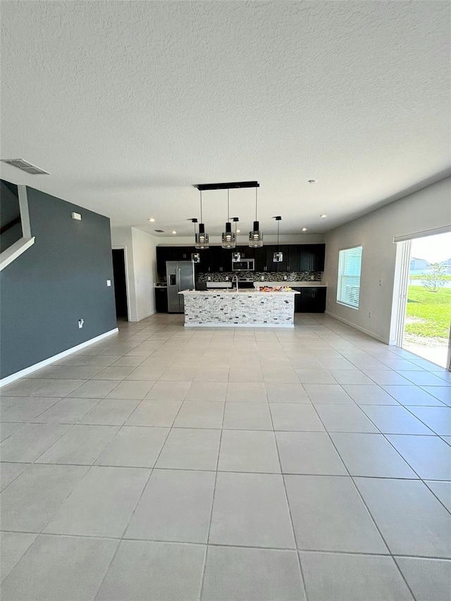 unfurnished living room featuring light tile patterned floors and a textured ceiling