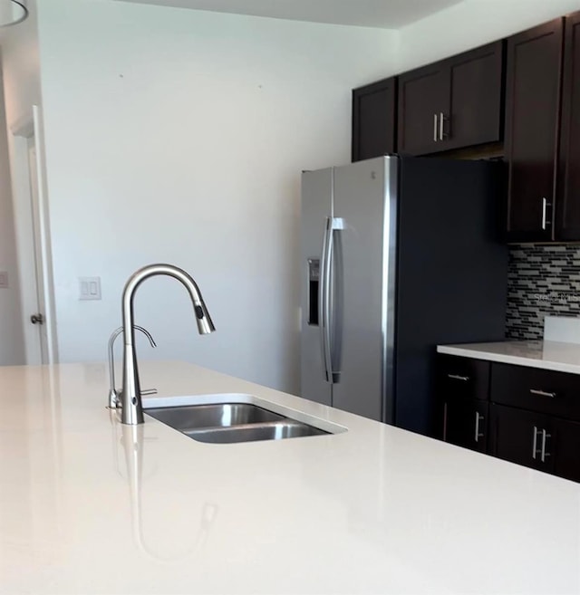 kitchen with dark brown cabinets, sink, stainless steel refrigerator with ice dispenser, and tasteful backsplash