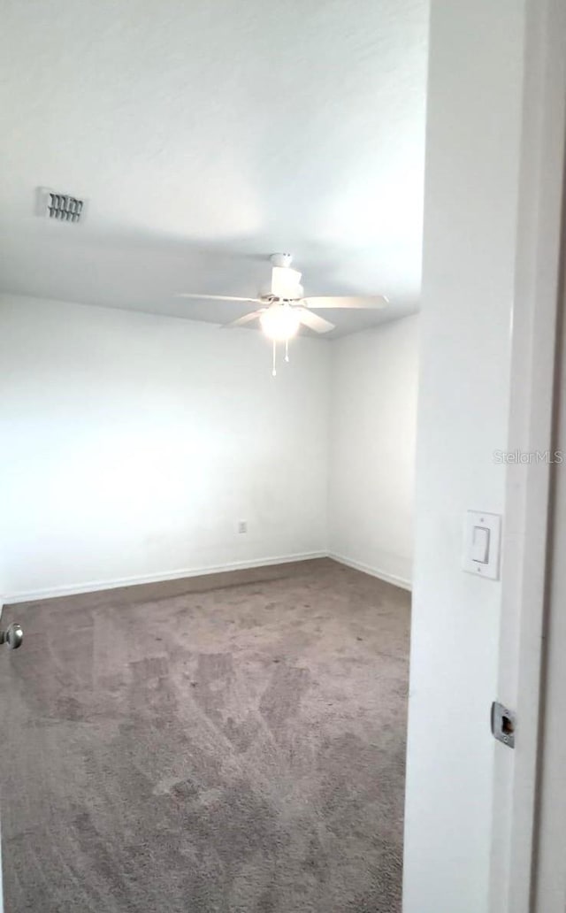 empty room with dark carpet and ceiling fan