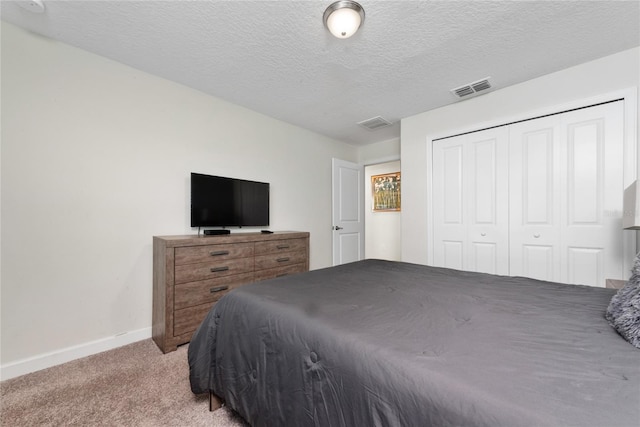 carpeted bedroom featuring a textured ceiling and a closet