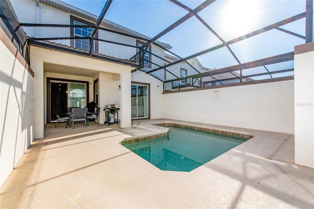 view of swimming pool with a patio, glass enclosure, and a grill