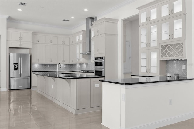 kitchen featuring tasteful backsplash, wall chimney range hood, white cabinetry, stainless steel appliances, and crown molding