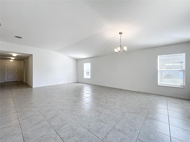 spare room featuring a notable chandelier, lofted ceiling, and light tile patterned floors