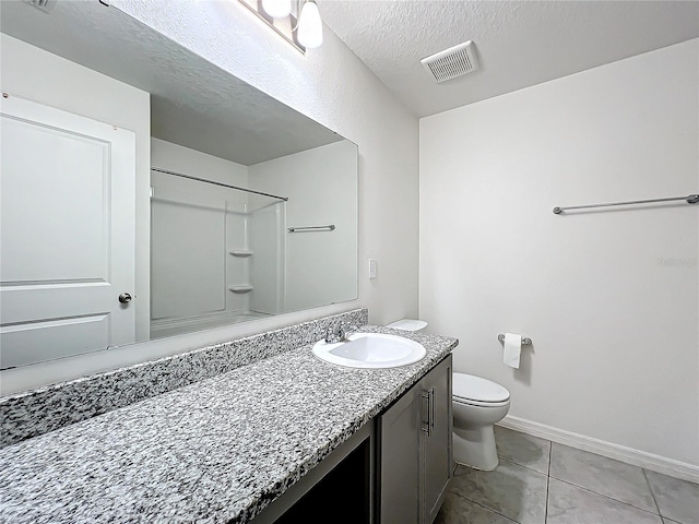 bathroom with a textured ceiling, walk in shower, toilet, vanity, and tile patterned floors