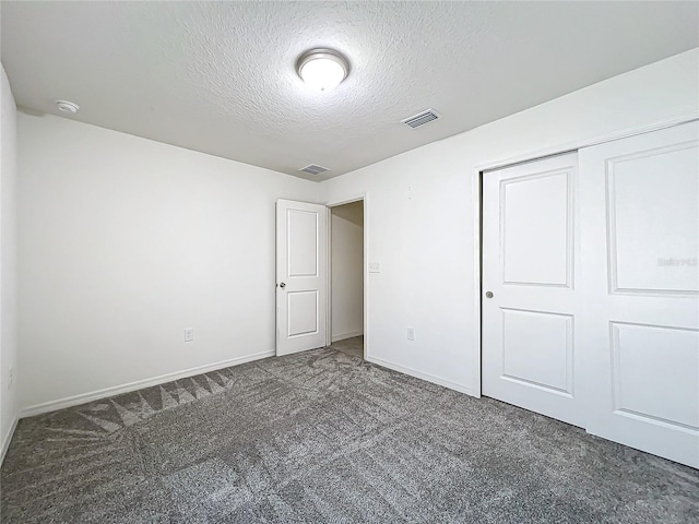 unfurnished bedroom featuring a closet, a textured ceiling, and dark colored carpet