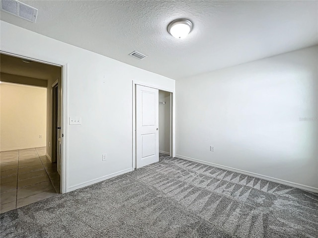 unfurnished bedroom featuring a textured ceiling and dark colored carpet