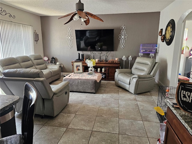 living room featuring ceiling fan, light tile patterned floors, and a textured ceiling