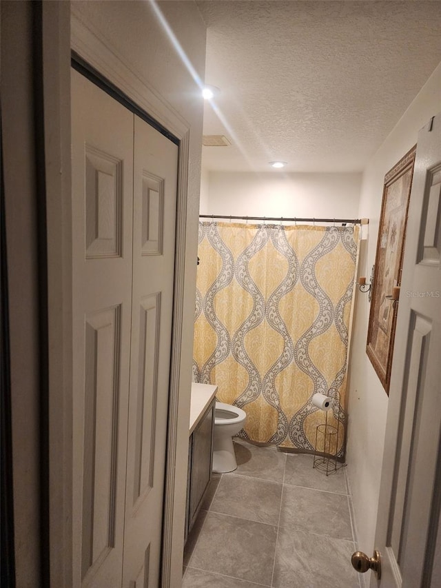 bathroom with a textured ceiling, toilet, and vanity