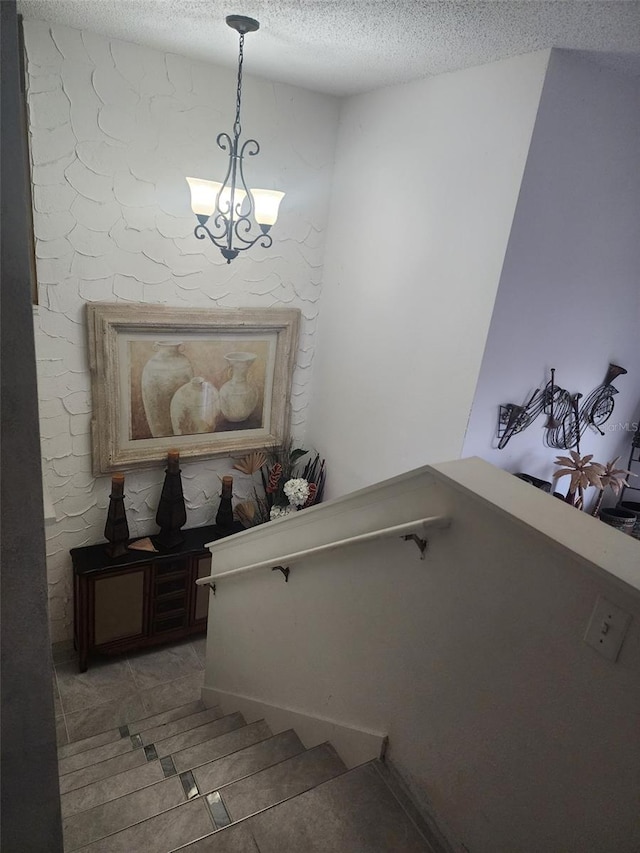 staircase featuring an inviting chandelier and a textured ceiling