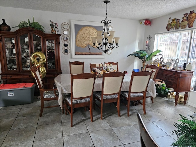 dining room with a textured ceiling, tile patterned floors, and a notable chandelier