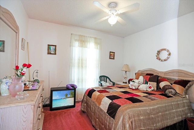 bedroom featuring ceiling fan, a textured ceiling, and dark carpet