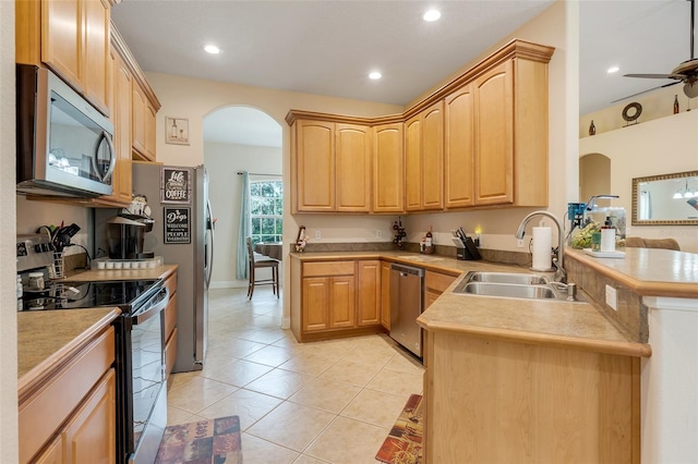 kitchen with kitchen peninsula, sink, light tile patterned flooring, light brown cabinetry, and appliances with stainless steel finishes