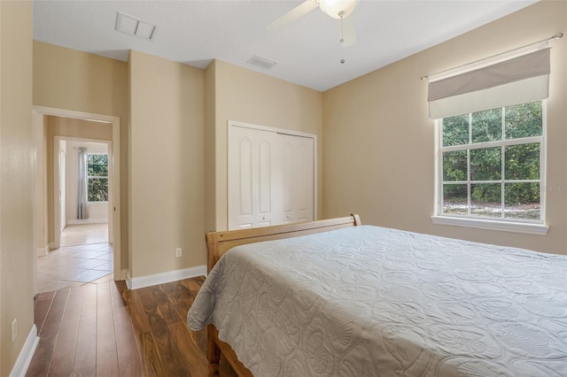 bedroom with dark hardwood / wood-style floors, a closet, and ceiling fan