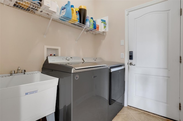 washroom with sink, light tile patterned floors, and separate washer and dryer