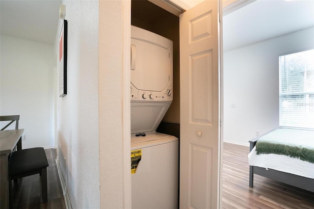 clothes washing area featuring hardwood / wood-style floors and stacked washing maching and dryer