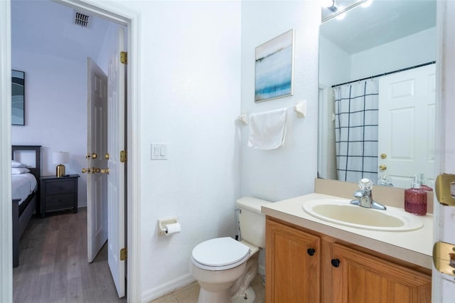 bathroom with hardwood / wood-style floors, vanity, toilet, and walk in shower