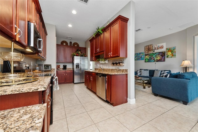 kitchen featuring sink, light stone countertops, appliances with stainless steel finishes, and light tile patterned floors