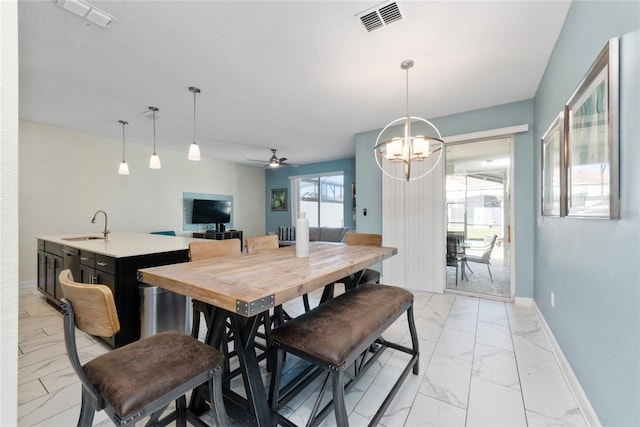 dining area with sink and ceiling fan with notable chandelier