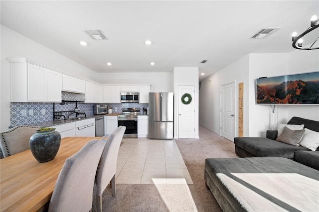 kitchen with tasteful backsplash, light tile patterned floors, white cabinetry, a notable chandelier, and stainless steel appliances