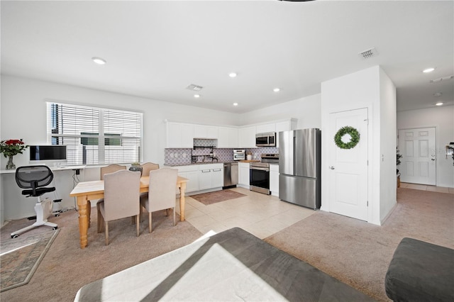 kitchen with light colored carpet, white cabinetry, tasteful backsplash, and stainless steel appliances