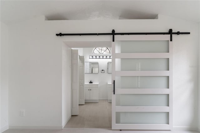 interior space featuring built in shelves, a barn door, sink, and vaulted ceiling