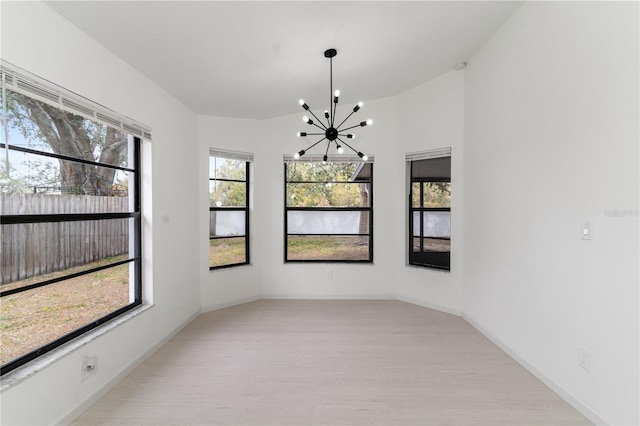 unfurnished dining area with an inviting chandelier and light wood-type flooring