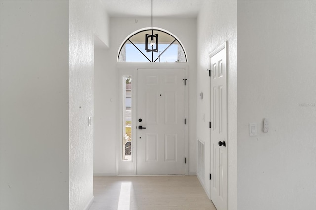 foyer entrance featuring a towering ceiling and light hardwood / wood-style floors