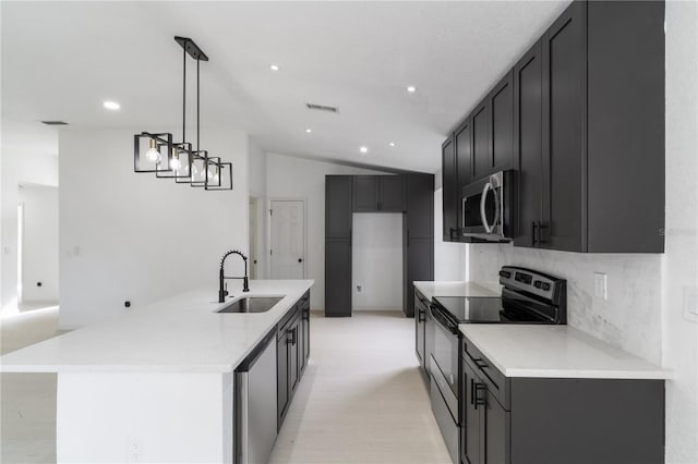 kitchen featuring black / electric stove, sink, hanging light fixtures, and a center island with sink