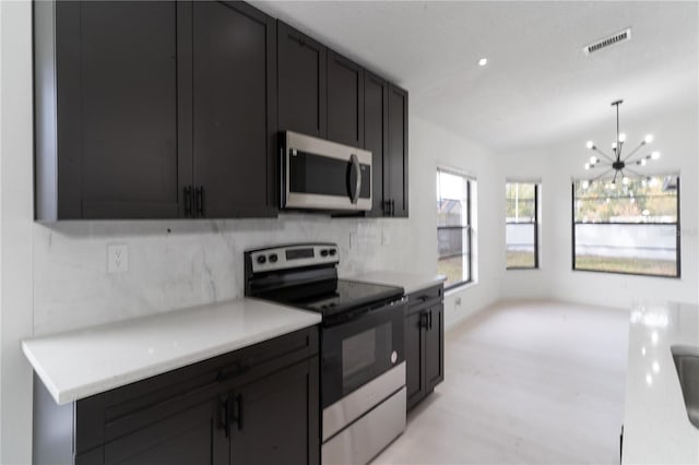 kitchen featuring appliances with stainless steel finishes, pendant lighting, a notable chandelier, and backsplash