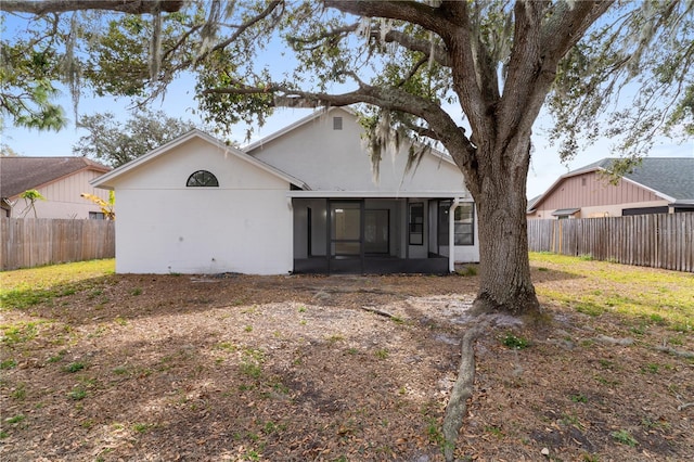 back of house featuring a sunroom and a lawn