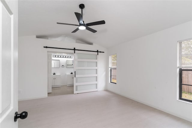 unfurnished room featuring lofted ceiling, a barn door, and ceiling fan