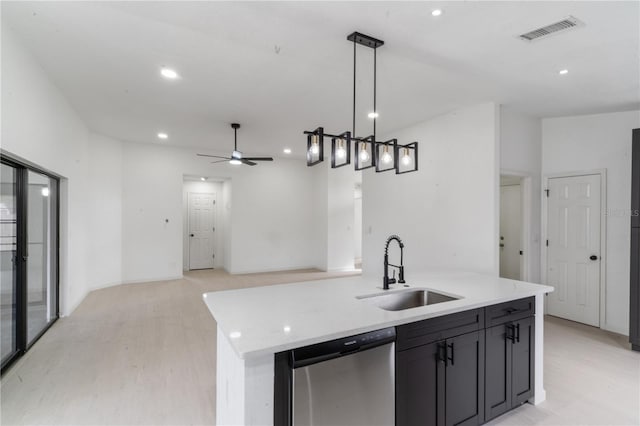 kitchen featuring sink, light hardwood / wood-style flooring, a kitchen island with sink, hanging light fixtures, and stainless steel dishwasher