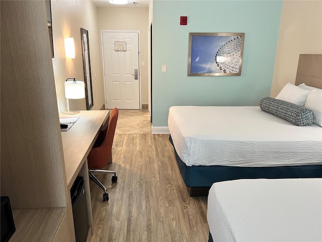 bedroom with built in desk and light wood-type flooring