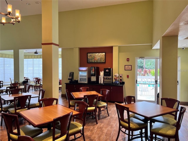 dining area featuring light hardwood / wood-style floors, a towering ceiling, and ceiling fan with notable chandelier