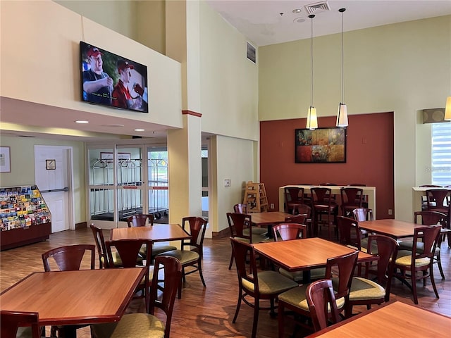 dining room with a towering ceiling and dark hardwood / wood-style floors