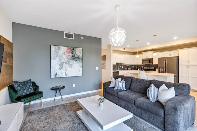 living room with a notable chandelier, sink, and light tile patterned floors