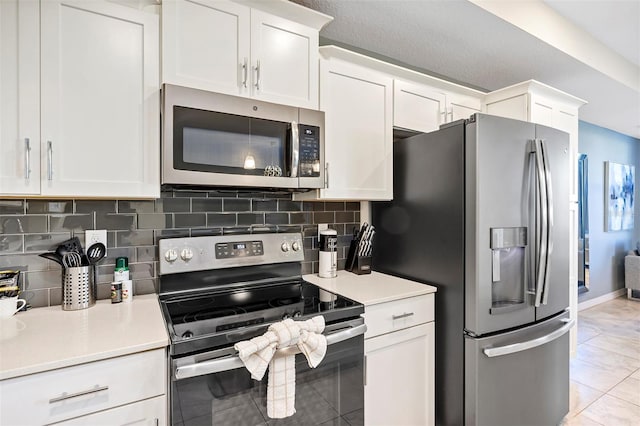 kitchen with appliances with stainless steel finishes, white cabinets, tasteful backsplash, and light tile patterned flooring