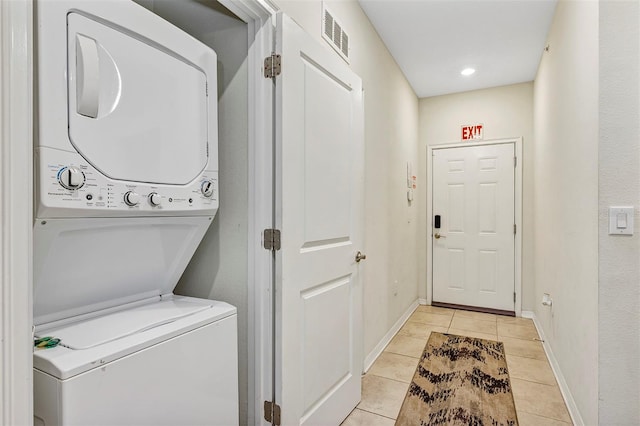 washroom featuring stacked washer and dryer and light tile patterned floors