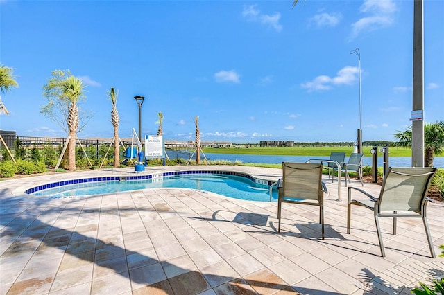 view of swimming pool with a patio area and a water view