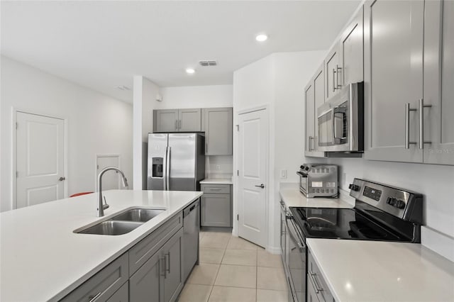 kitchen featuring light tile patterned flooring, stainless steel appliances, gray cabinets, and sink