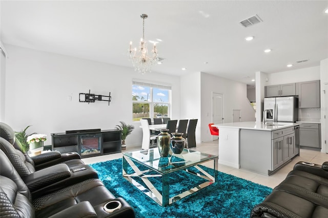 living room with light tile patterned flooring, sink, and an inviting chandelier