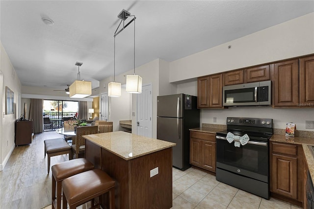 12527 Floridays Resort Dr Unit E-103, Orlando, FL 32821 - kitchen featuring stainless steel appliances, a center island, a breakfast bar area, open floor plan, and ceiling fan