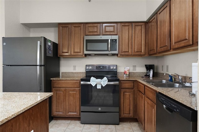 kitchen featuring light tile patterned floors, appliances with stainless steel finishes, sink, and light stone counters