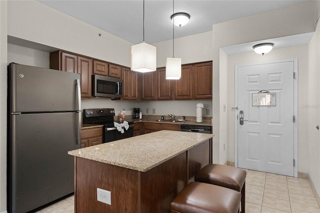 12527 Floridays Resort Dr Unit E-103, Orlando, FL 32821 - kitchen featuring appliances with stainless steel finishes, light tile patterned floors, a center island, decorative light fixtures, and light stone counters