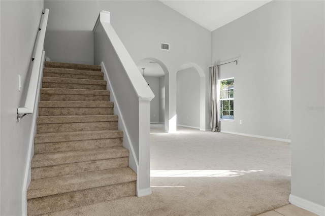 stairs featuring carpet floors and high vaulted ceiling