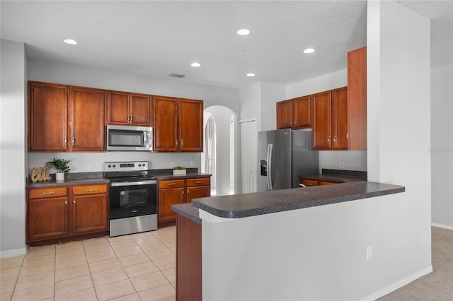 kitchen featuring kitchen peninsula, a textured ceiling, stainless steel appliances, and light tile patterned floors