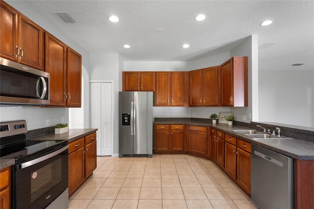 kitchen featuring sink, stainless steel appliances, a textured ceiling, and light tile patterned floors