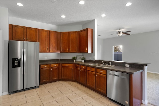 kitchen with kitchen peninsula, sink, light tile patterned floors, appliances with stainless steel finishes, and a textured ceiling