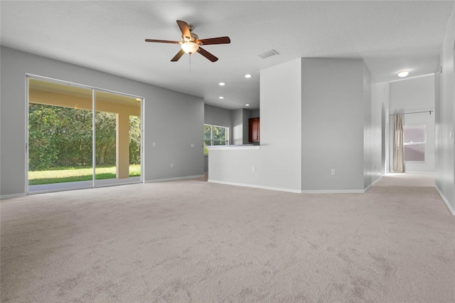 unfurnished living room with light carpet, a textured ceiling, and ceiling fan